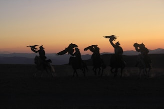 Sunset over the Andes mountains with silhouettes of riders and shamans gathered in a circle.