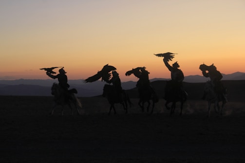Sunset over the Andes mountains with silhouettes of riders and shamans gathered in a circle.