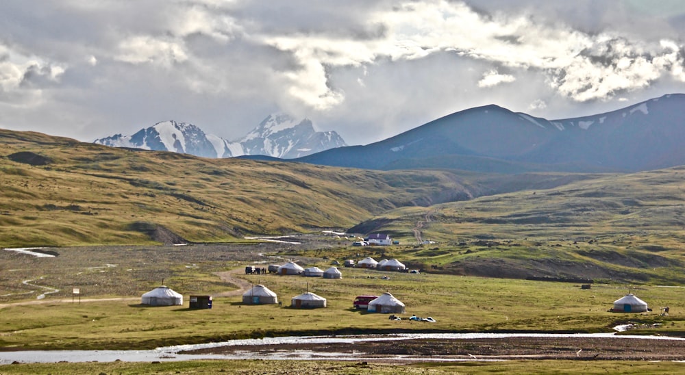 white and black cars on green grass field near mountain under white clouds during daytime