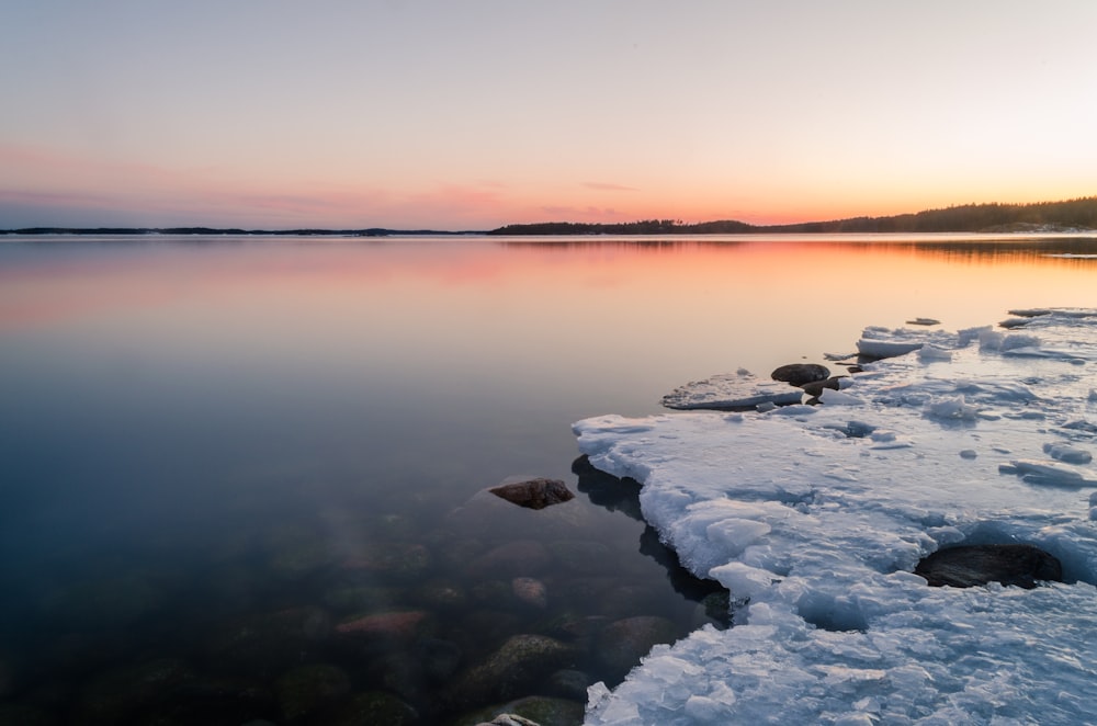 rocky shore with rocks on water under blue sky during sunset