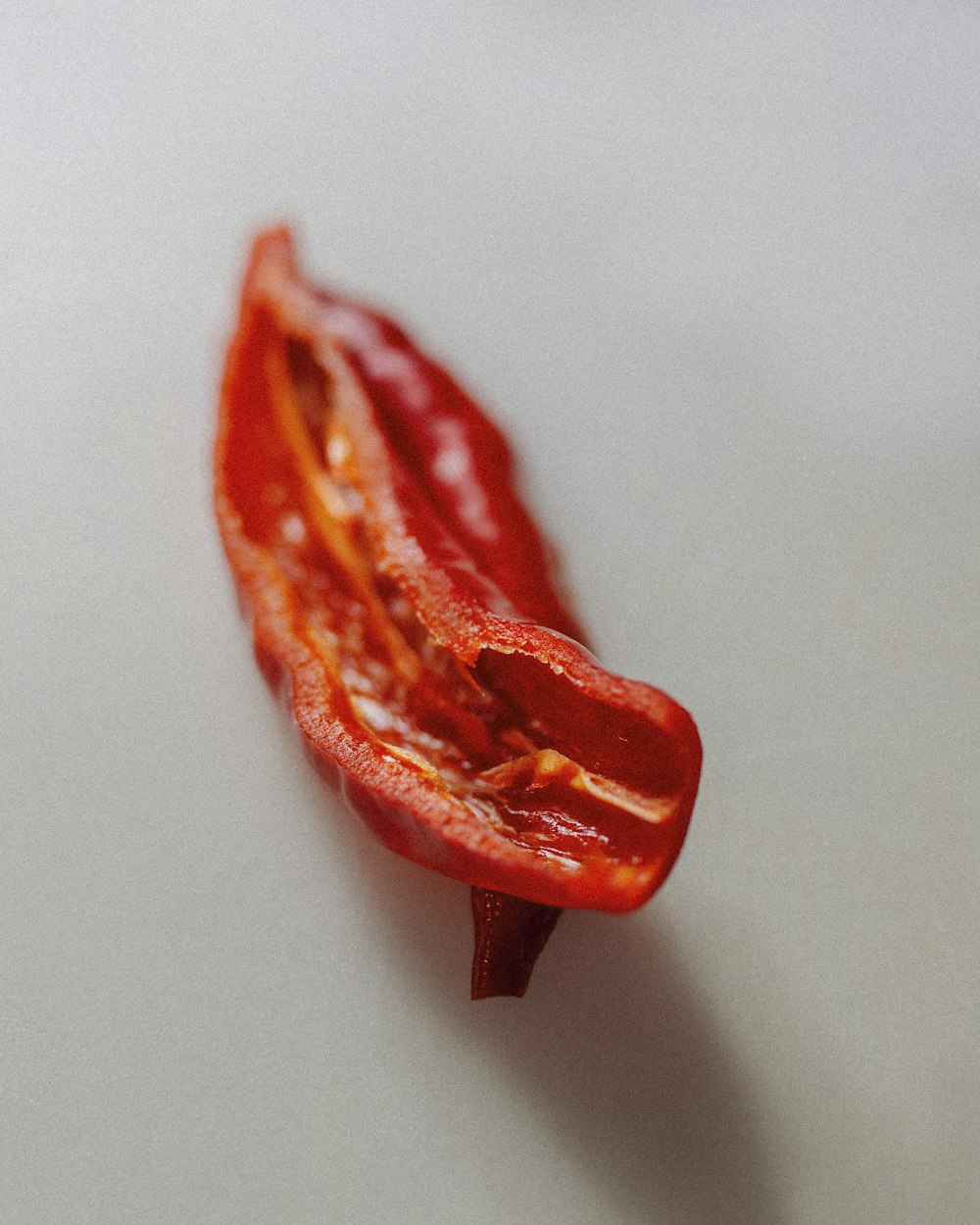 a close up of a red pepper on a white surface