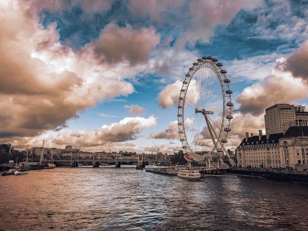 ferris wheel beside body of water under cloudy sky during daytime