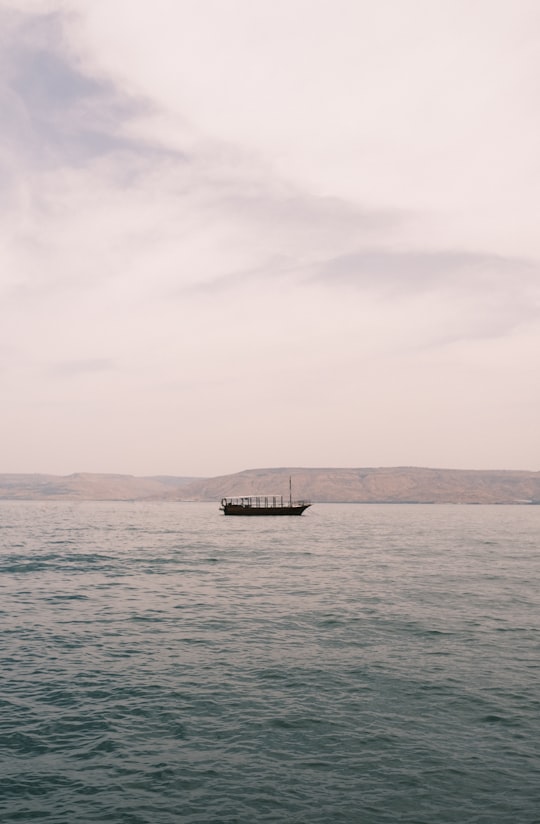 black boat on sea under white sky during daytime in Tiberias Israel