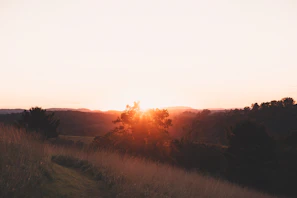 Sunset over a quiet countryside landscape with gentle hills.