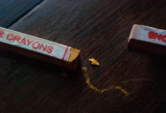 A close-up of colorful broken crayons arranged in a heart shape on a wooden table.