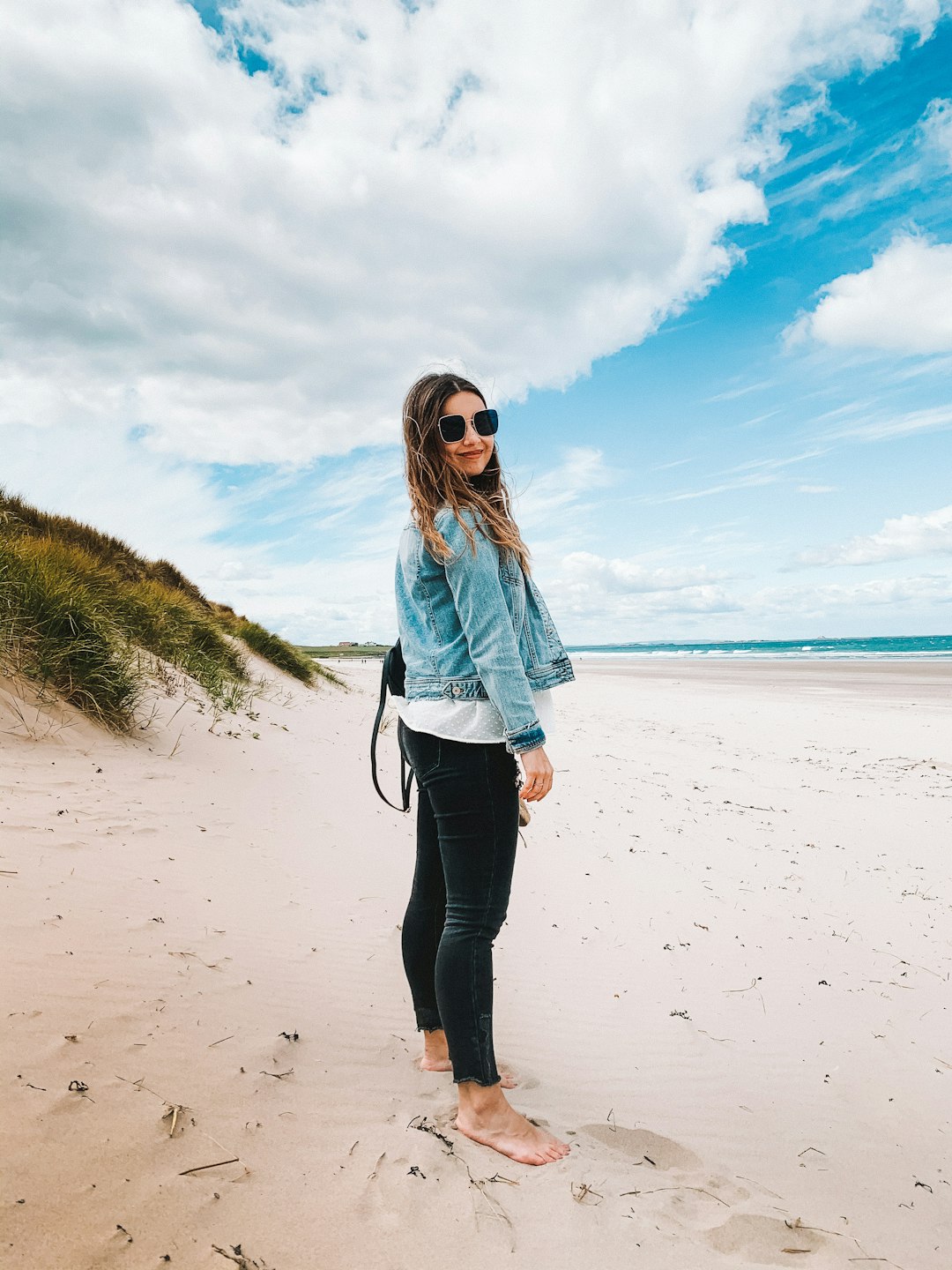 woman in blue denim jacket standing on beach during daytime