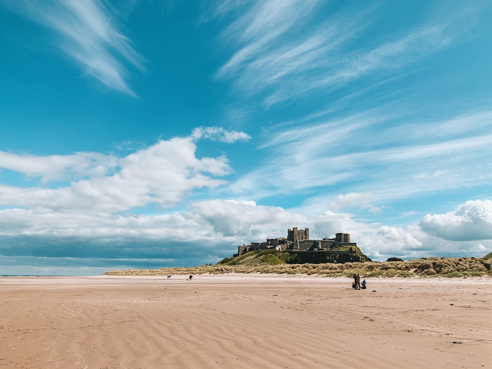 brown sand beach under blue sky and white clouds during daytime