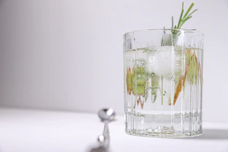 A refreshing gin cocktail garnished with fresh herbs and citrus slices on a modern glass.
