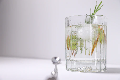 A refreshing blue cocktail served in a chilled glass with ice cubes and a sprig of rosemary.