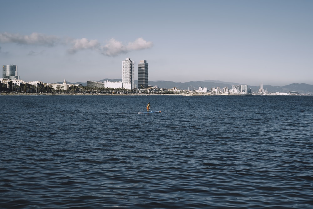 Menschen, die tagsüber auf dem Meer in der Nähe von Stadtgebäuden schwimmen