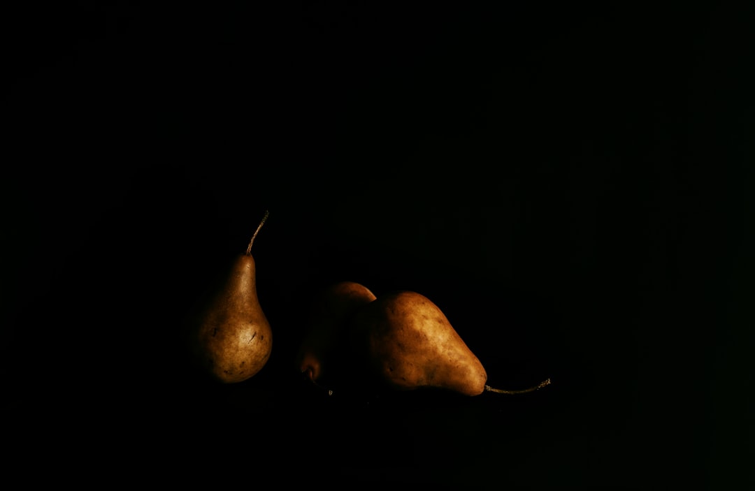 two brown pear fruits on black surface