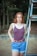 woman in blue and white stripe tank top and blue denim jeans standing beside gray metal