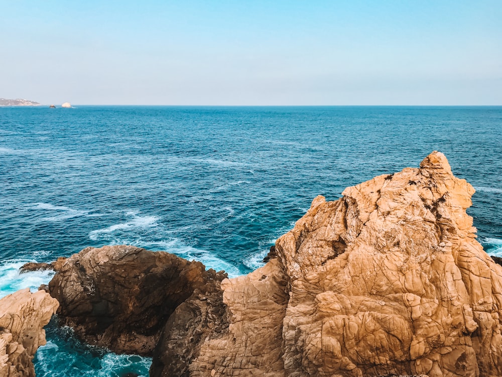 Formation rocheuse brune au bord de la mer bleue pendant la journée