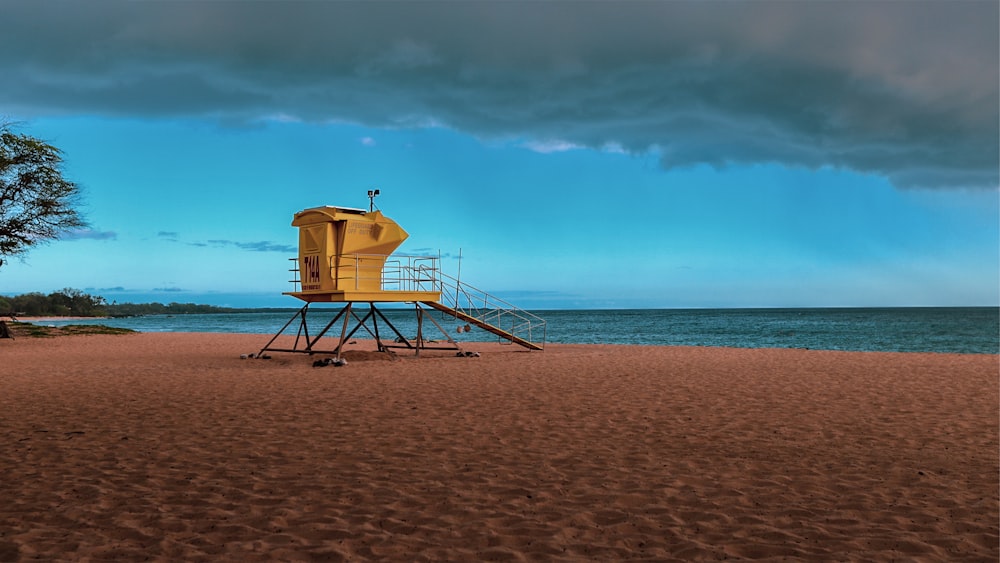 Casetta di salvataggio in legno marrone sulla spiaggia durante il giorno