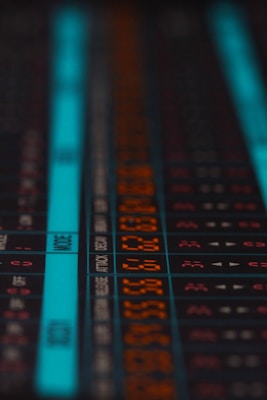 A close-up of an electronic display panel featuring numbers and text in a digital, pixelated format. The display includes both orange and blue segments, with various numbers and terms like 'MODE' and 'ATTACK' visible. The image conveys a sense of technology or computing, likely related to audio or technical equipment.