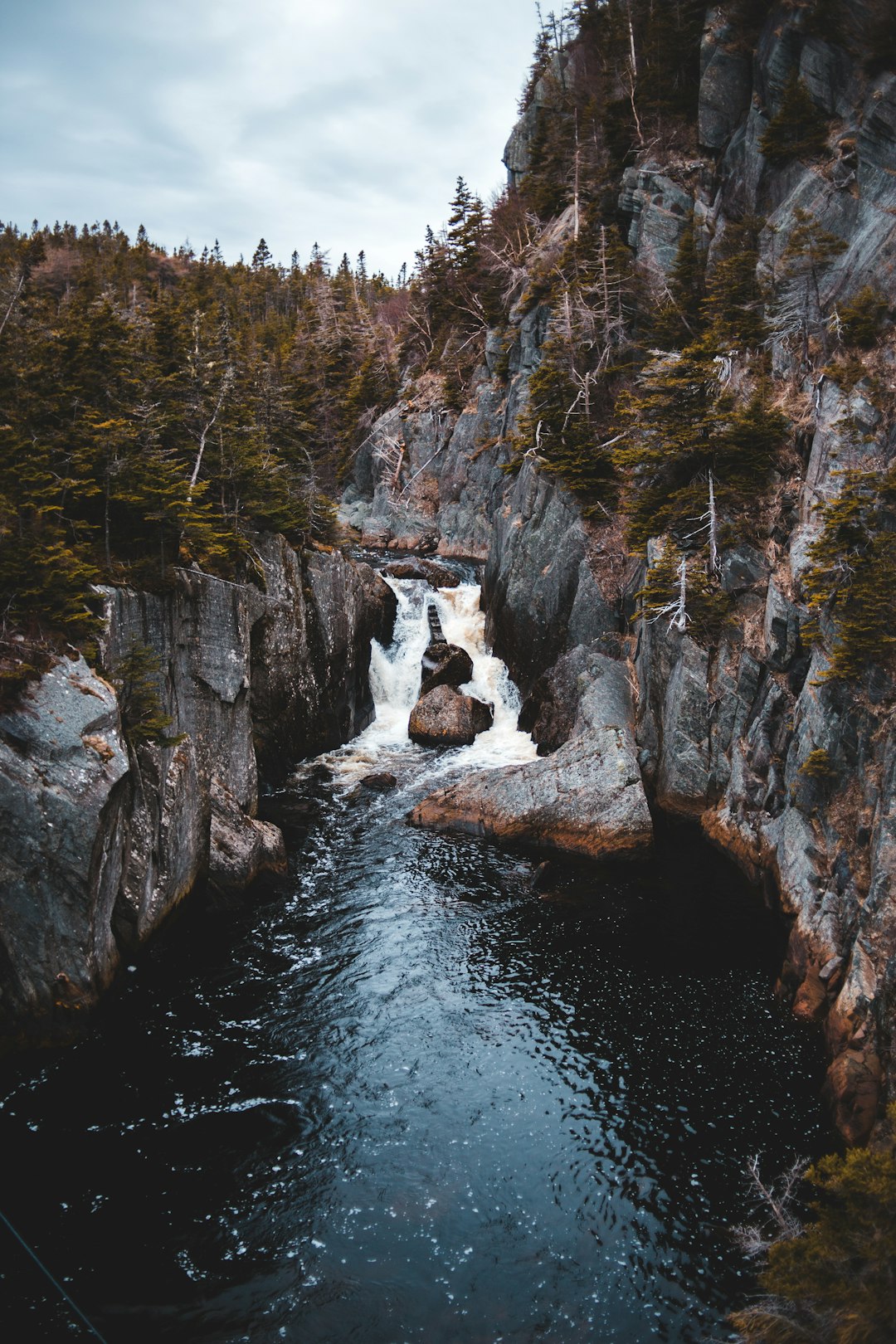 river between brown rocky mountain during daytime