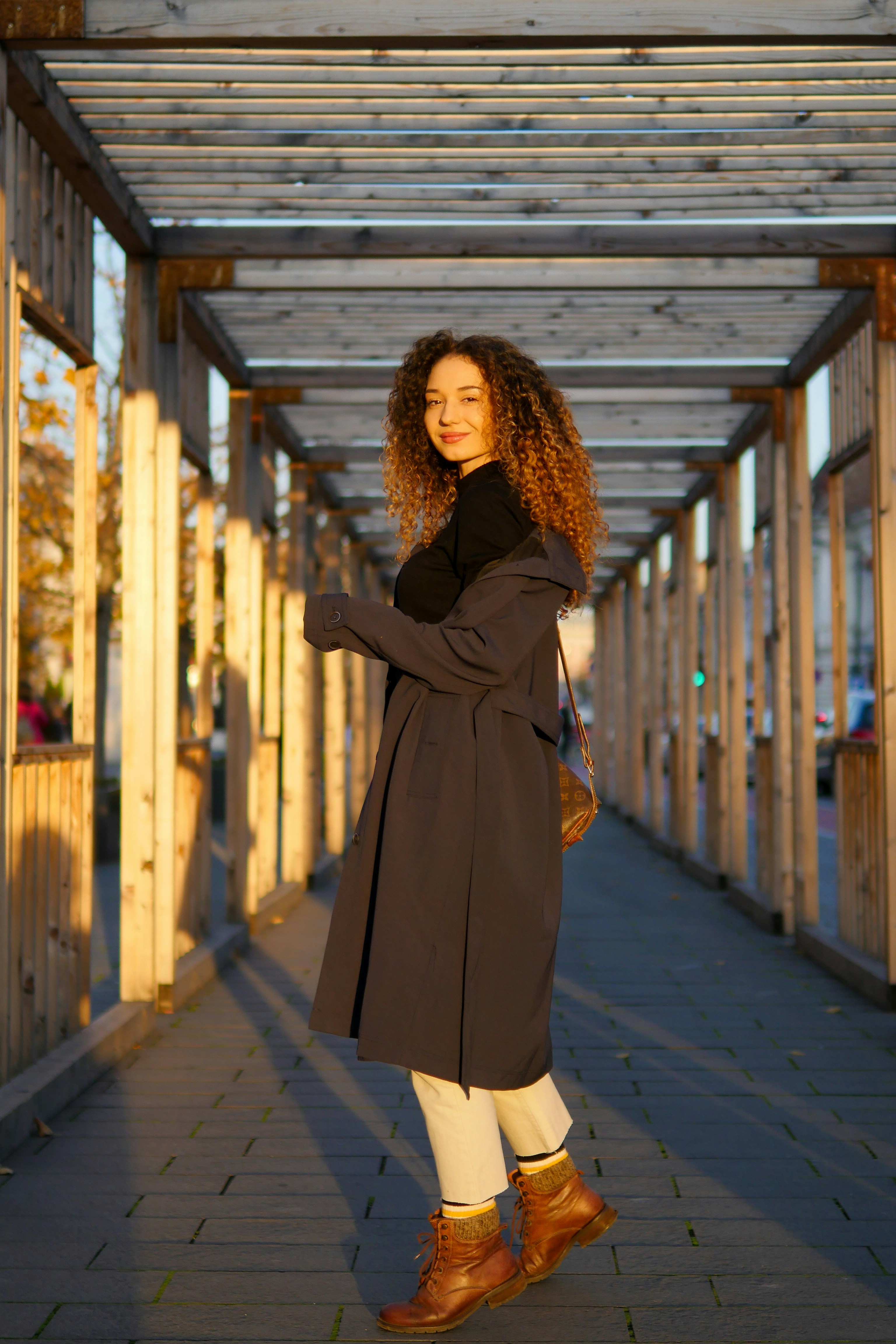 woman in black coat standing on sidewalk during daytime