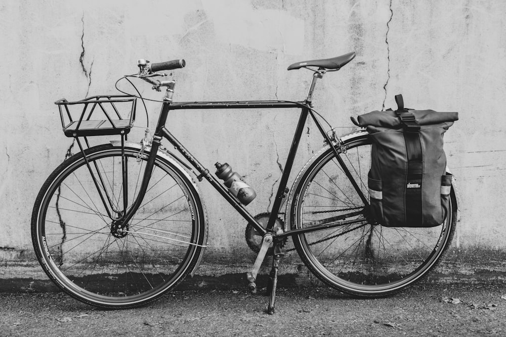 grayscale photo of bicycle leaning on wall