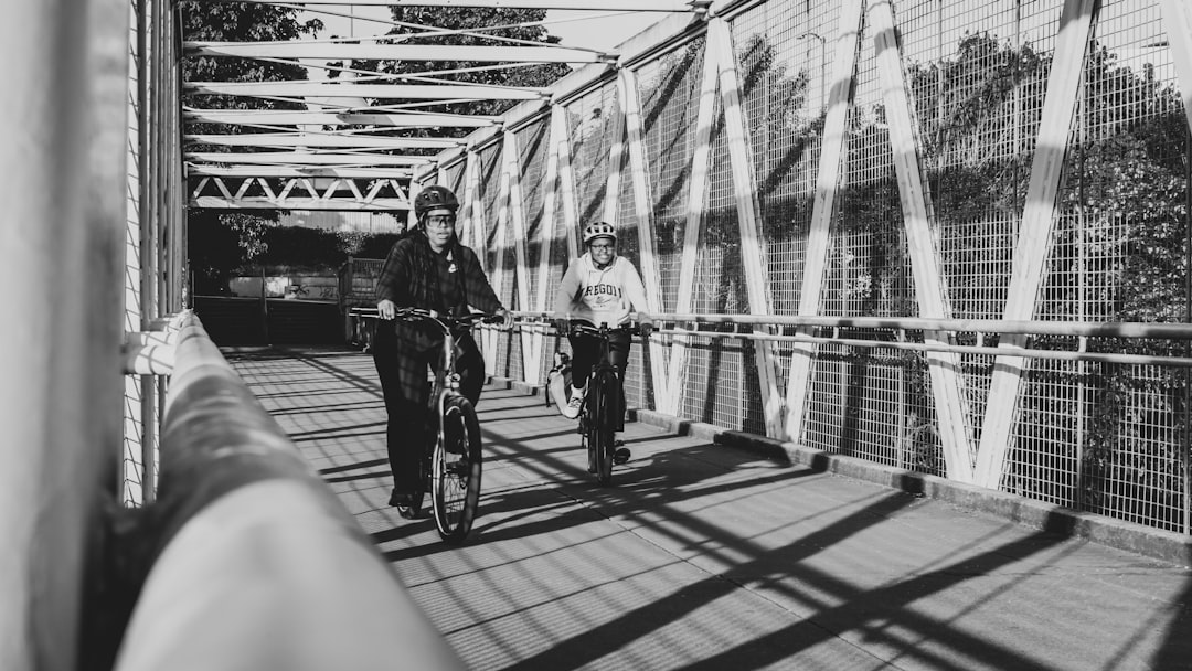 grayscale photo of man and woman riding bicycle