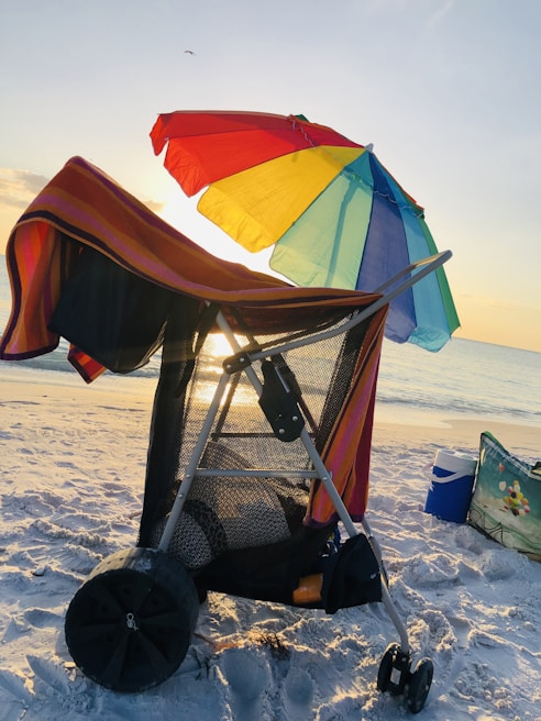 A compact beach wagon loaded with colorful towels and sun hats on golden sand