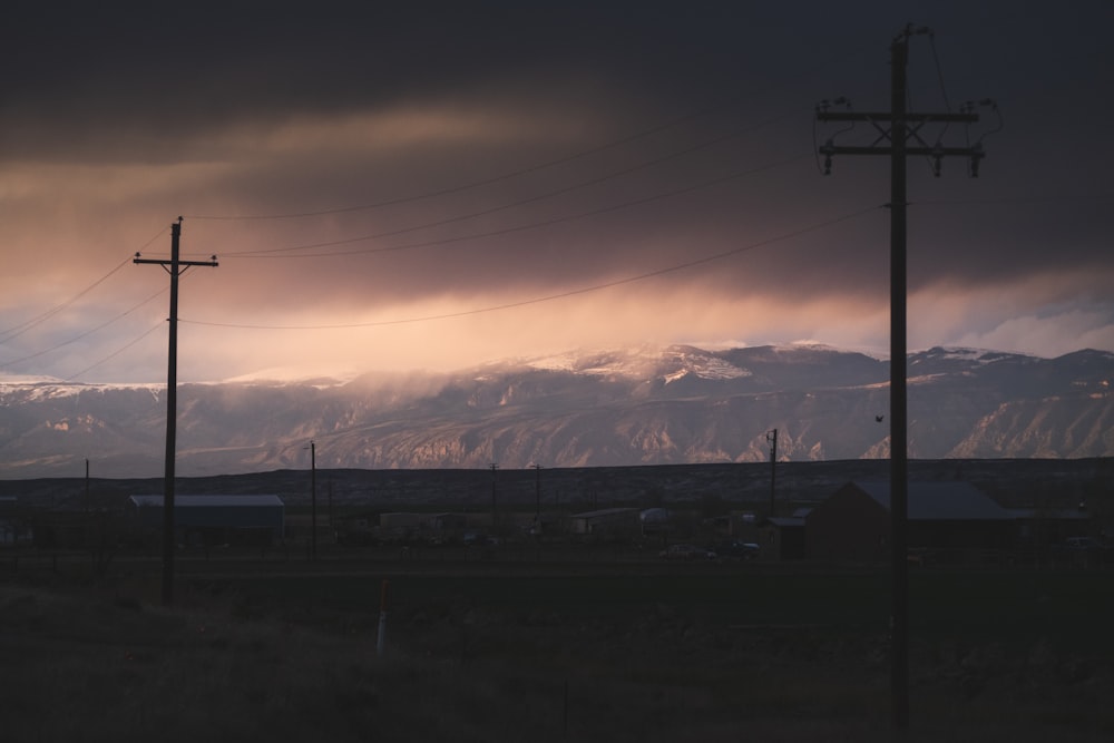 black electric post near snow covered mountain during daytime