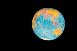 A globe displaying various countries and oceans, with a focus on the Indian Ocean region. The globe features vibrant colors to distinguish different nations and bodies of water, set against a stark black background that highlights its spherical shape.
