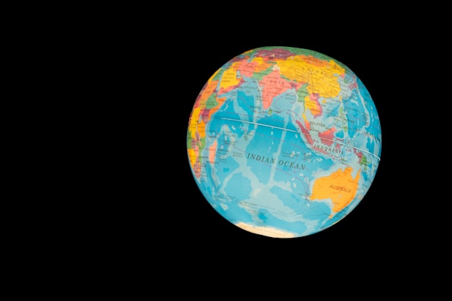 A globe displaying various countries and oceans, with a focus on the Indian Ocean region. The globe features vibrant colors to distinguish different nations and bodies of water, set against a stark black background that highlights its spherical shape.