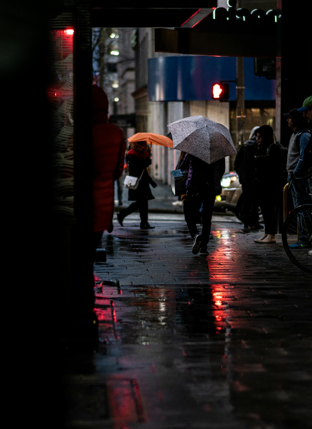 people walking on sidewalk with umbrella during daytime