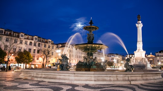 water fountain in the middle of the city during night time in Lisbon Portugal