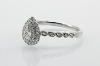 silver diamond studded ring on white surface