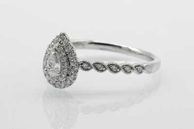 silver diamond studded ring on white surface