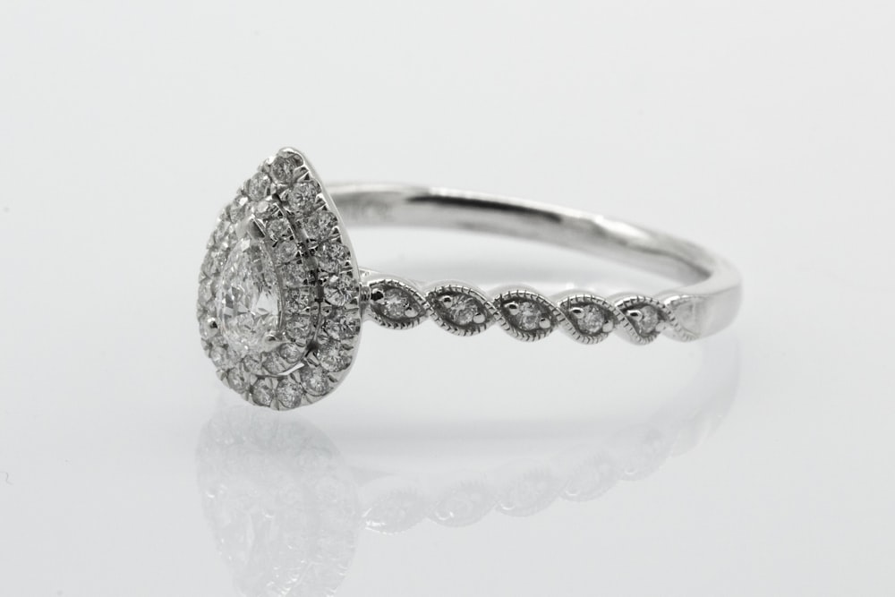 silver diamond studded ring on white surface