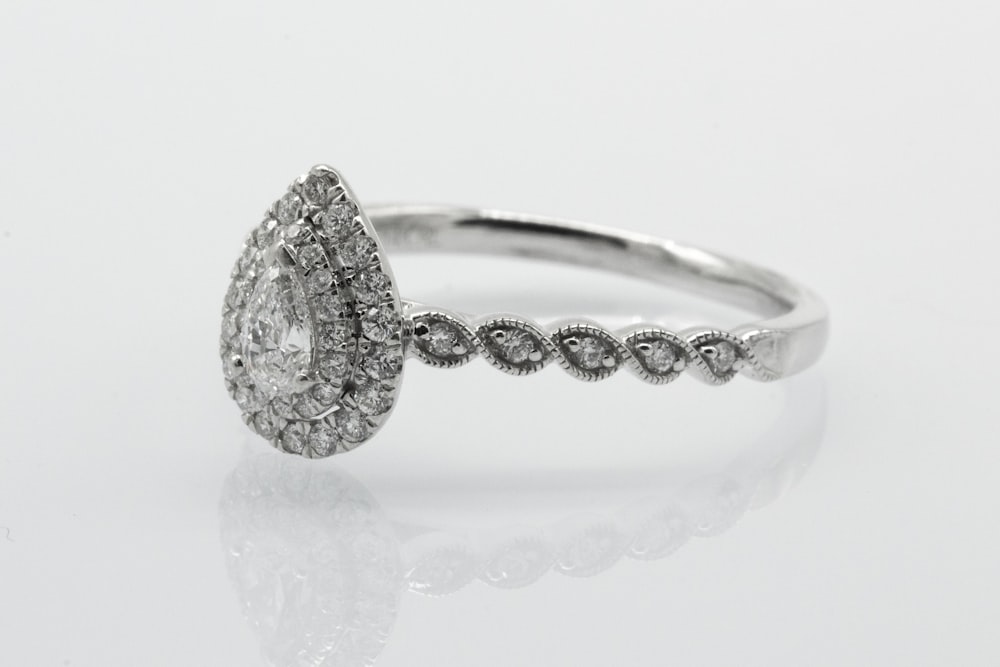 anel cravejado de diamante prateado na superfície branca