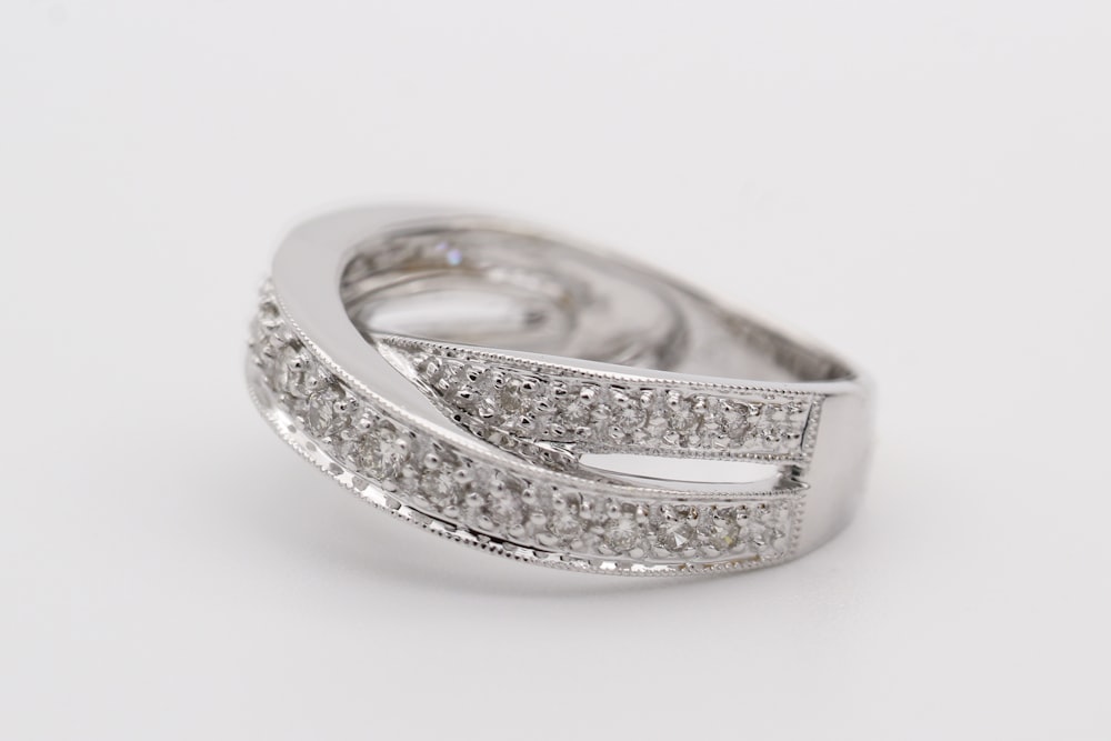 silver diamond ring on white surface