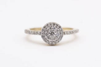 A sparkling diamond engagement ring with a round center stone surrounded by a halo of smaller diamonds, set on a band encrusted with additional diamonds.