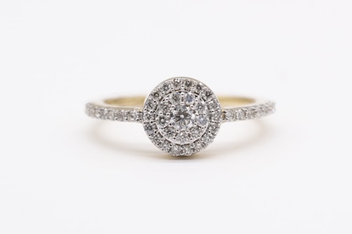 A sparkling diamond engagement ring with a round center stone surrounded by a halo of smaller diamonds, set on a band encrusted with additional diamonds.
