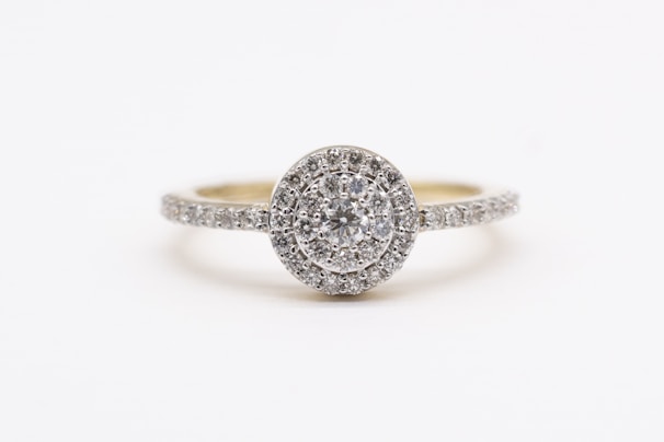 A sparkling diamond engagement ring with a round center stone surrounded by a halo of smaller diamonds, set on a band encrusted with additional diamonds.