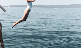 woman in white tank top and white shorts jumping on water during daytime