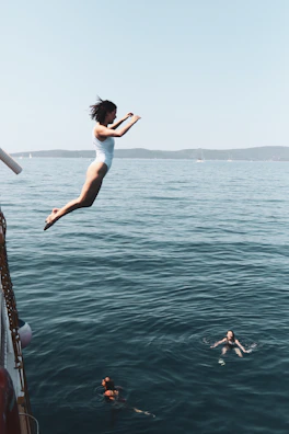 Swimmers diving into the calm Adriatic Sea from the ship's sun deck at sunrise.