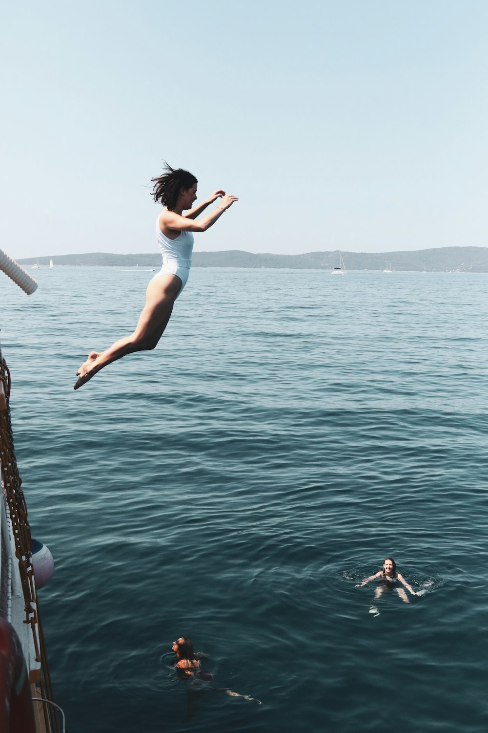 Frau in weißem Tanktop und weißen Shorts springt tagsüber auf Wasser