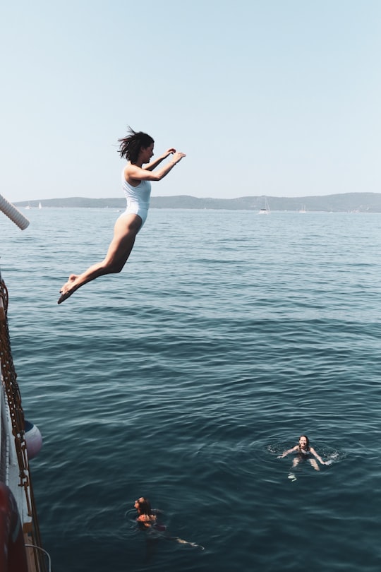 woman in white tank top and white shorts jumping on water during daytime in Hvar Croatia