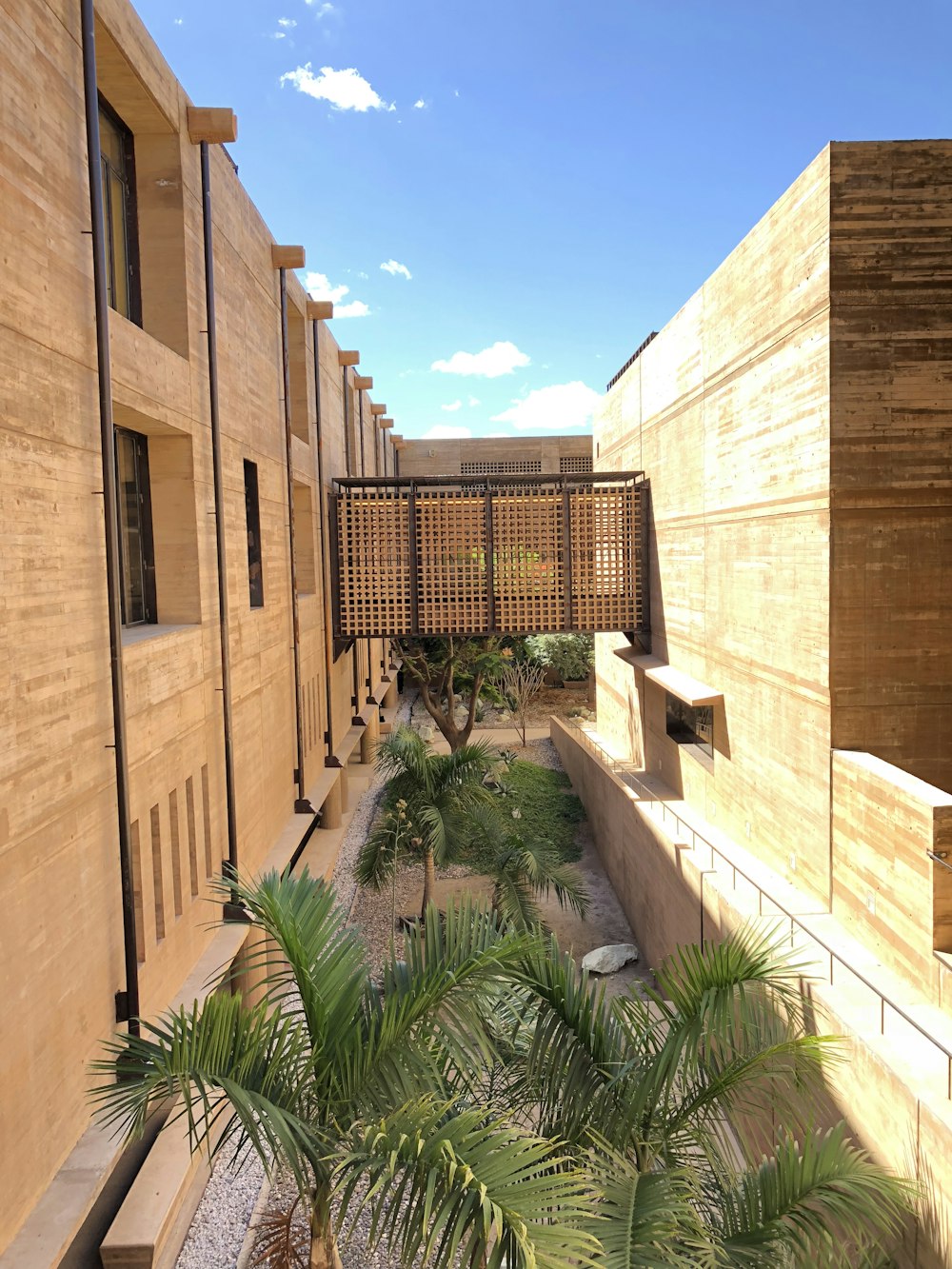 brown concrete building near green trees under blue sky during daytime