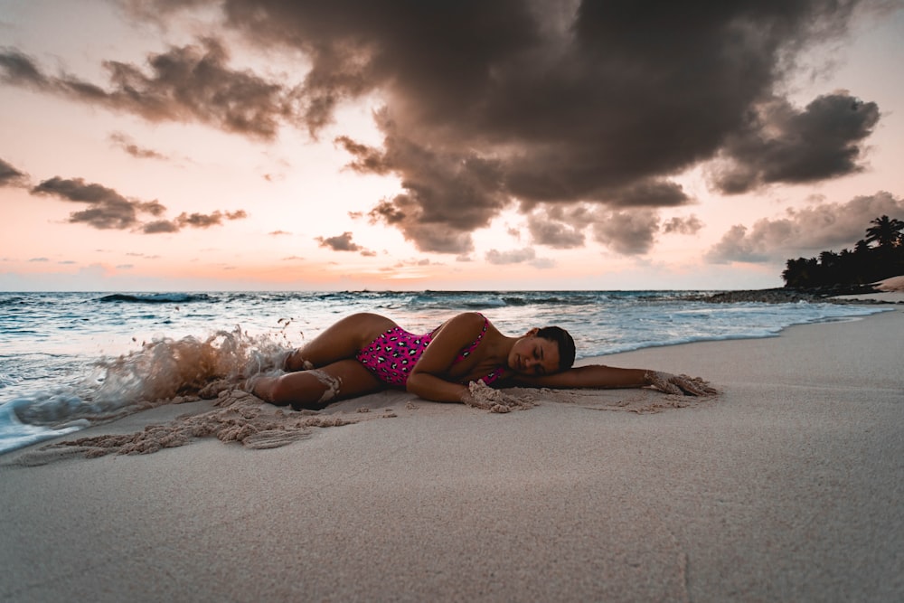 woman in purple bikini lying on beach during sunset