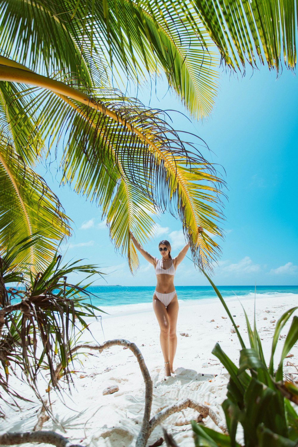 femme en bikini blanc debout sur la plage pendant la journée