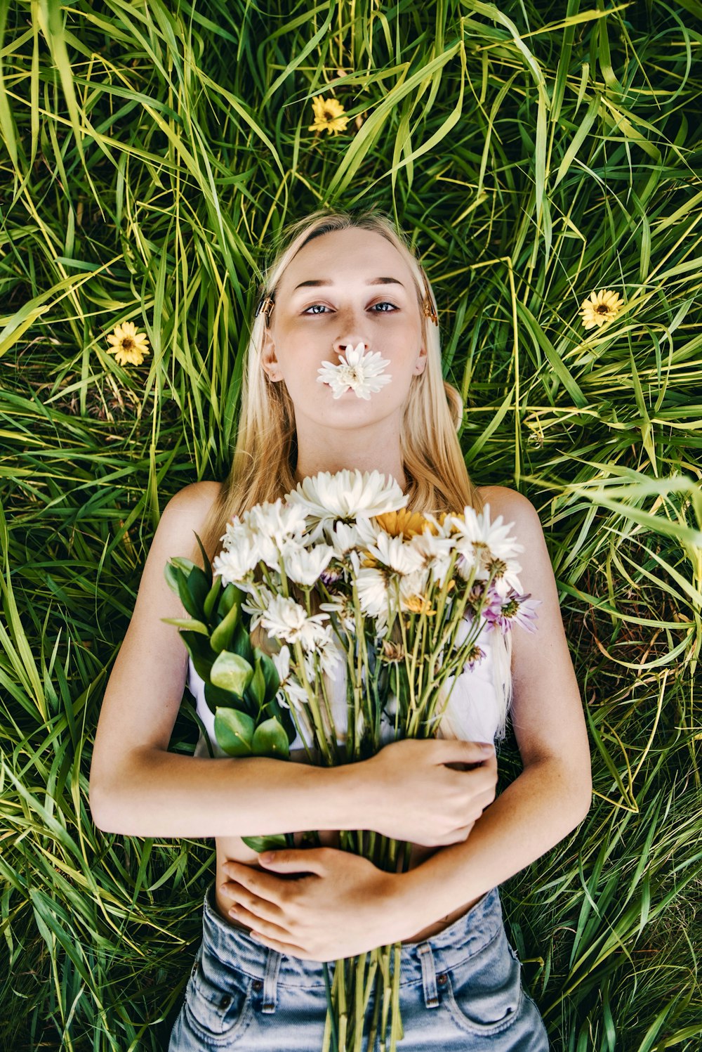 Frau in weißem Blumenkleid liegt auf grünem Grasfeld