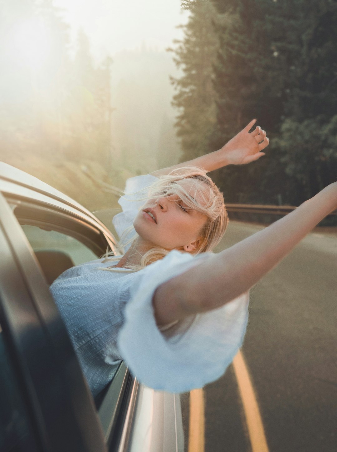 girl in white tank top and blue denim jeans sitting on car seat during daytime