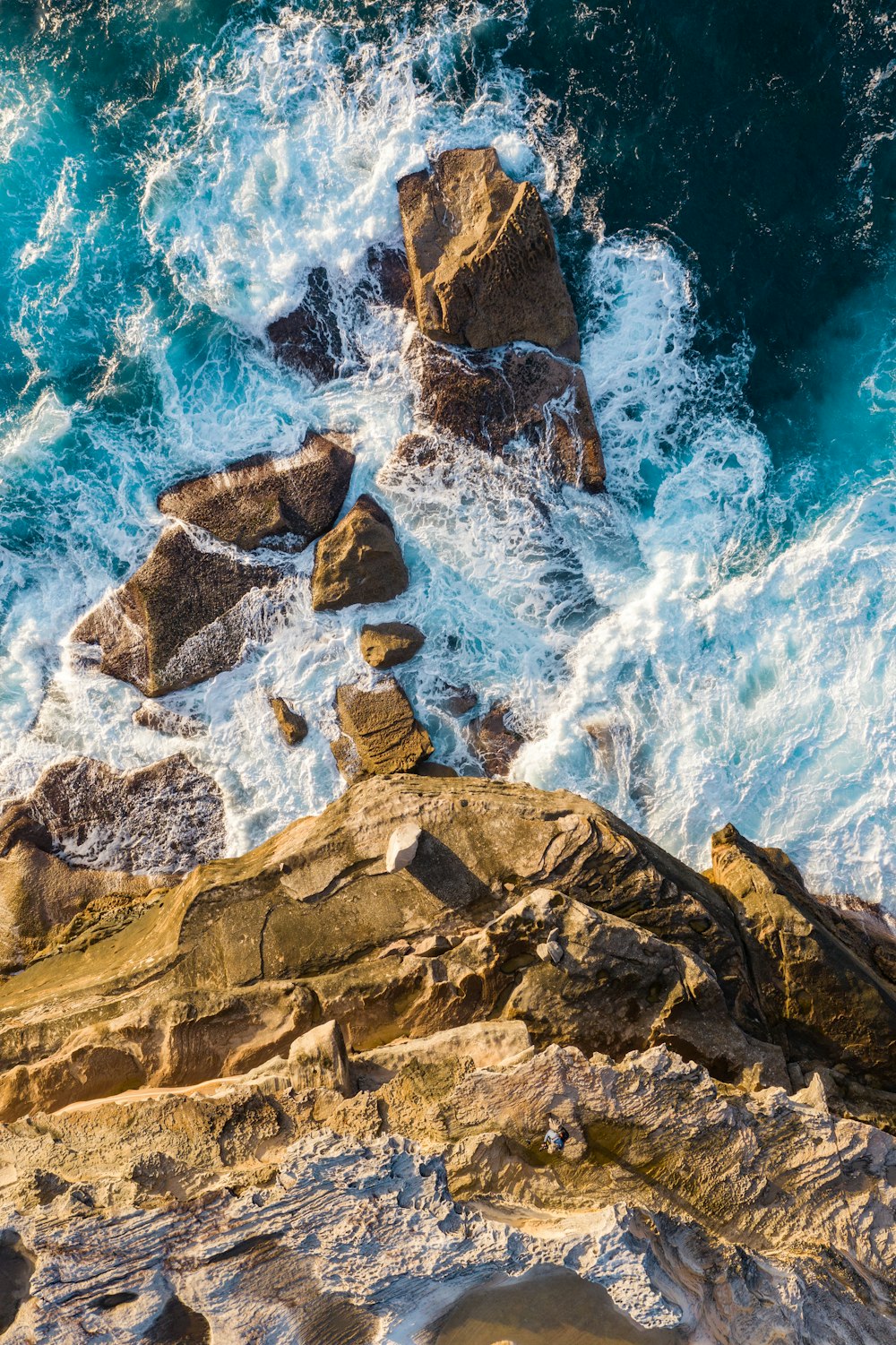 brown rocky mountain beside blue sea water during daytime