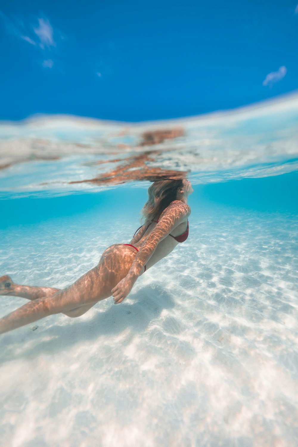 femme en bikini noir sautant sur l’eau