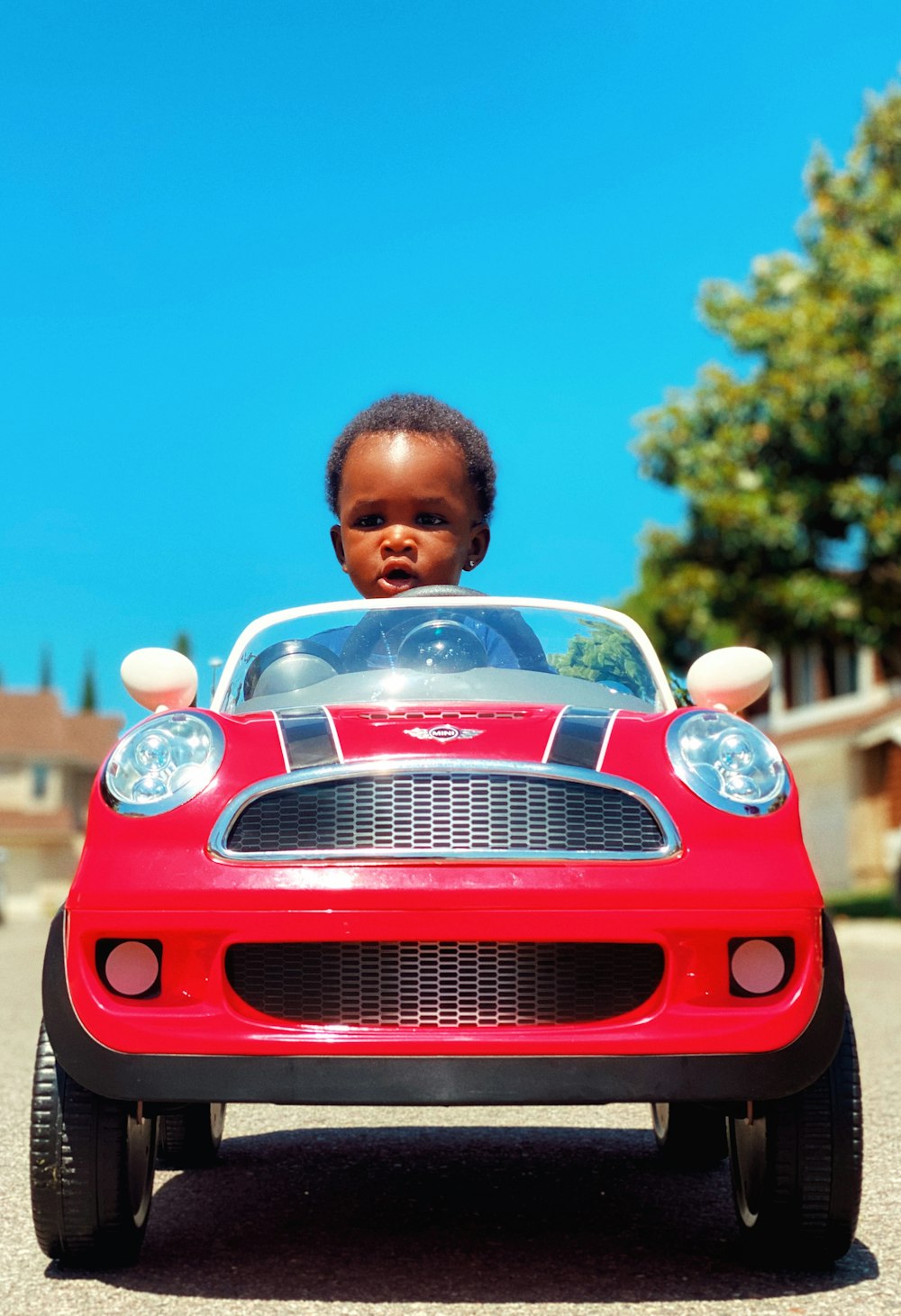 boy in white shirt standing beside red car
