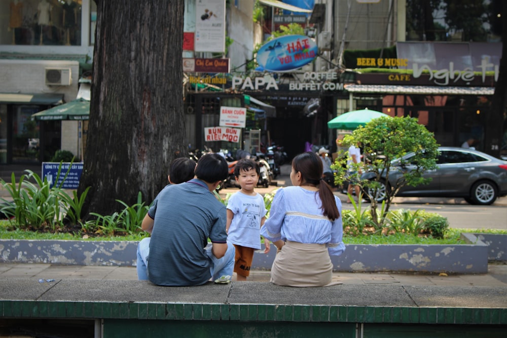 persone che si siedono sulla panchina verde vicino alla strada durante il giorno